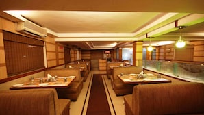 Un restaurant avec des banquettes et des tables, une allée centrale et un panneau lumineux au néon en arrière-plan.