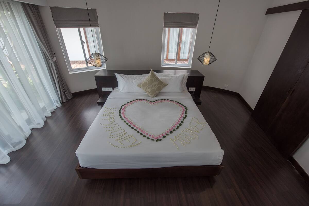 A neatly made bed with a heart-shaped decoration and a message on the bedspread.