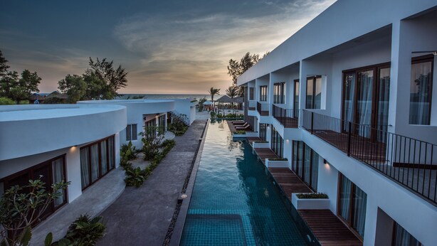 A modern resort with a swimming pool, multiple balconies, and a view of the ocean. - Ren Resort (Sihanoukville)