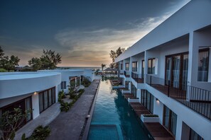 A modern resort with a swimming pool, multiple balconies, and a view of the ocean. - Ren Resort (Sihanoukville)