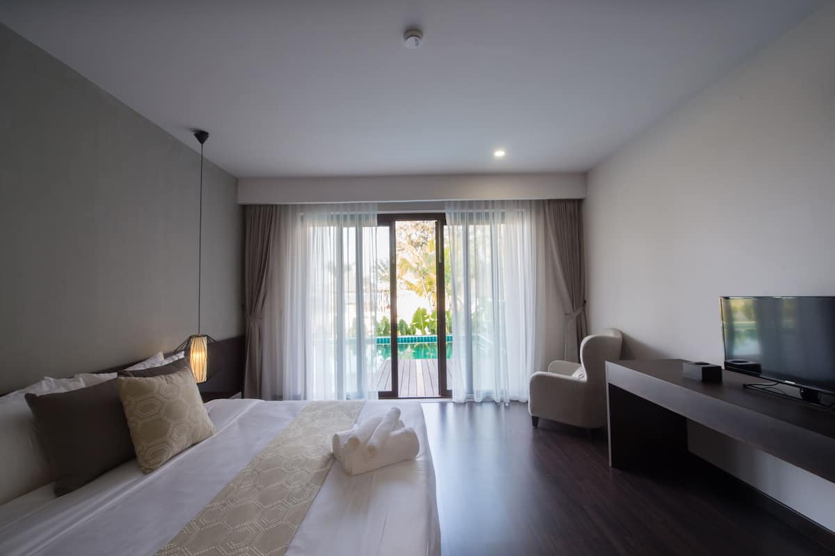 A modern hotel room with a large bed, a TV, and a balcony with curtains.