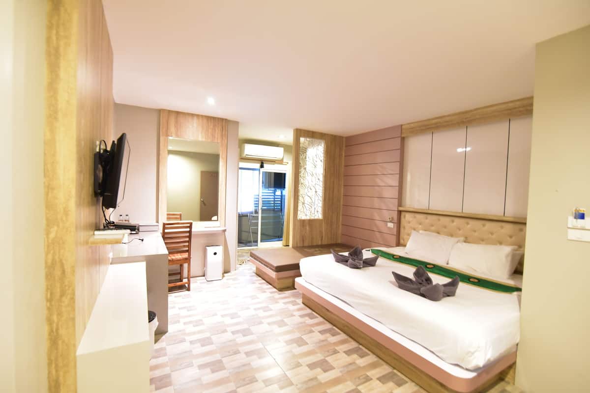 Habitación de hotel con cama, escritorio, silla, espejo y ventana.