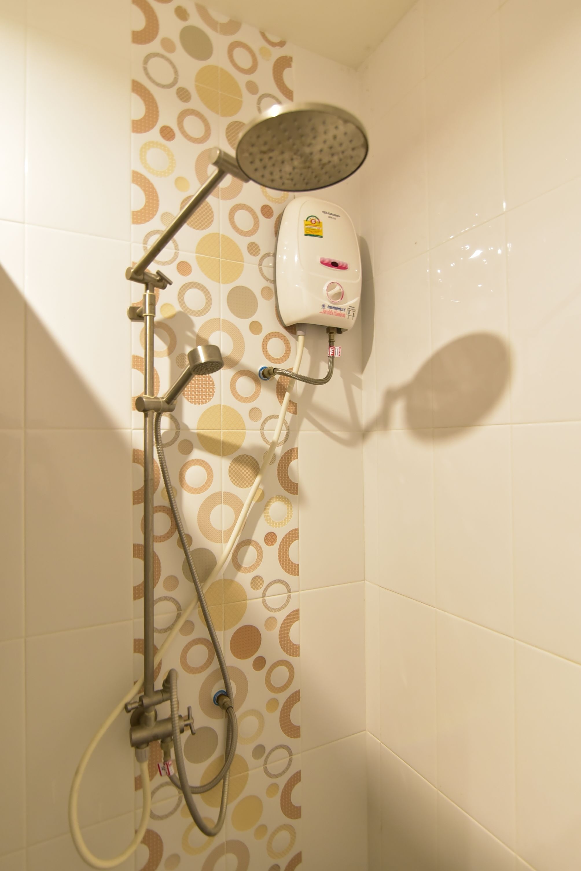 A shower with a handheld showerhead, a wall-mounted handheld showerhead, and a handheld shower hose.