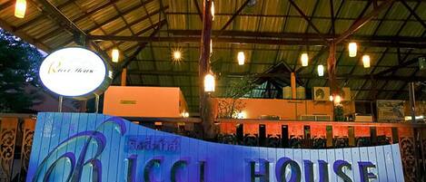 A sign for 'Ricci House' with a rustic, industrial-style roof and hanging lights.