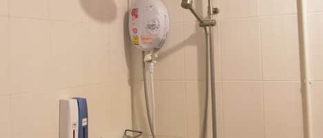 Een douche met een handdouche, een bedieningspaneel aan de muur en een glazen plank.