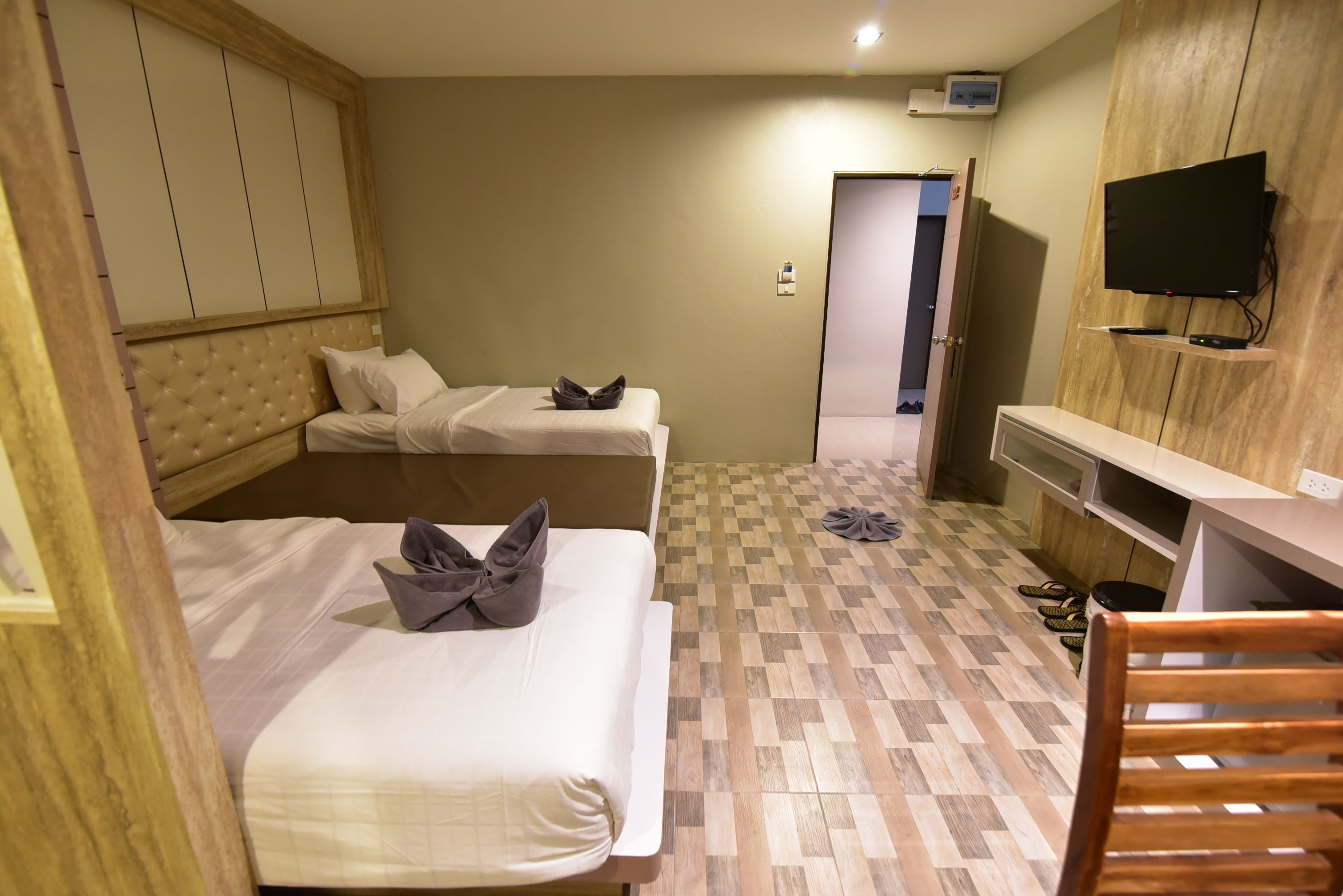 Une chambre d’hôtel avec deux lits, une télévision et une armoire en bois.