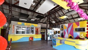 A reception area with a yellow counter, a reception desk, and a large window. - Ricci House Resort (Koh Lipe)