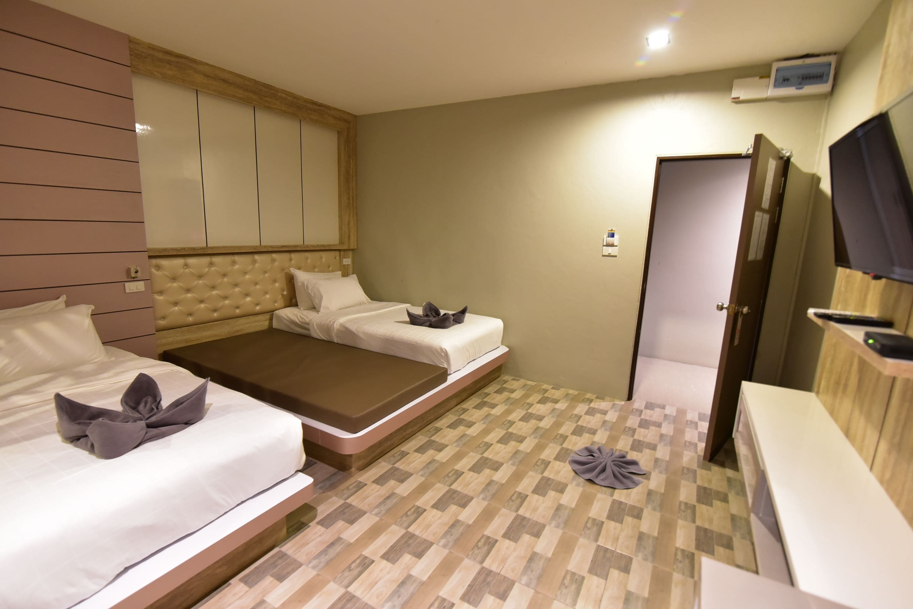 Habitación de hotel con dos camas, cabecero de madera, televisor de pantalla plana y un escritorio pequeño.