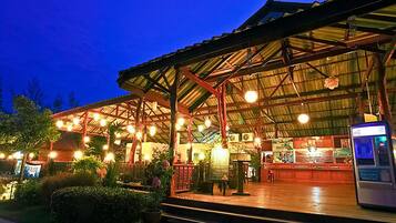 A covered outdoor area with a wooden deck, potted plants, and a ticket machine.
