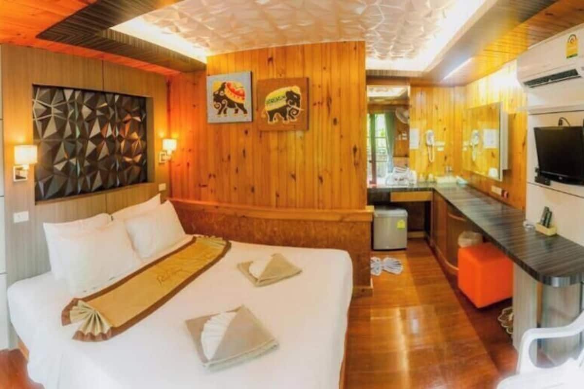 Una habitación de hotel con cama, escritorio, televisión y baño.