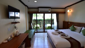 Una habitación de hotel con cama, escritorio, televisor y balcón con sillas.