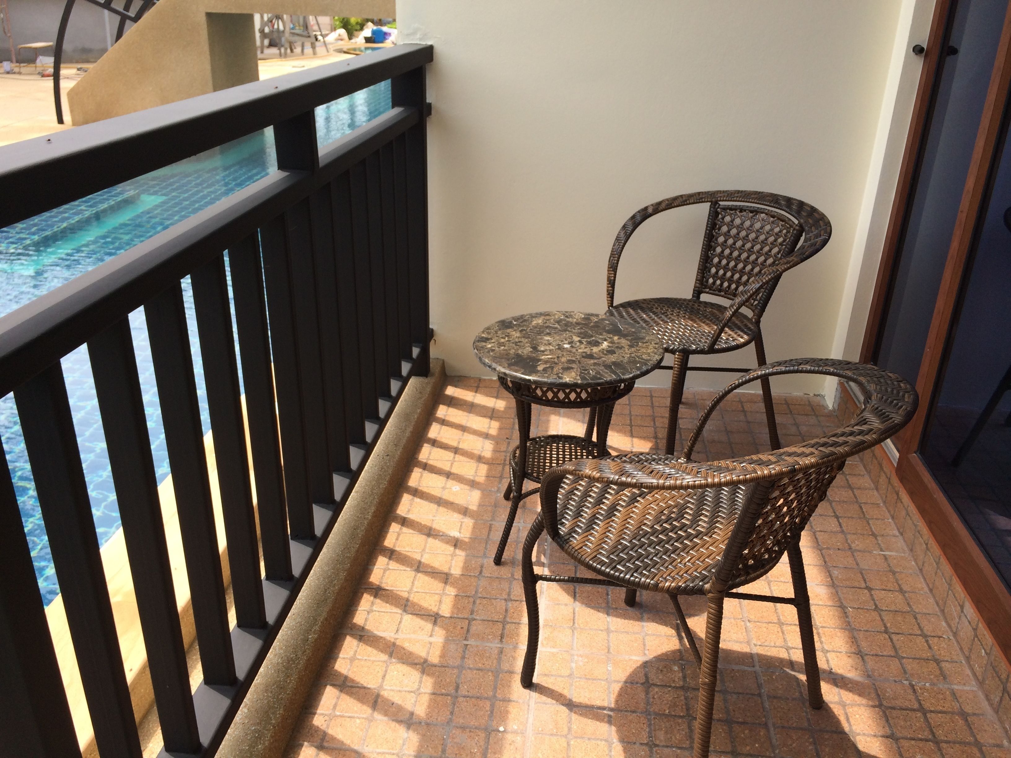 A balcony with a view of the ocean, two wicker chairs, and a small table.