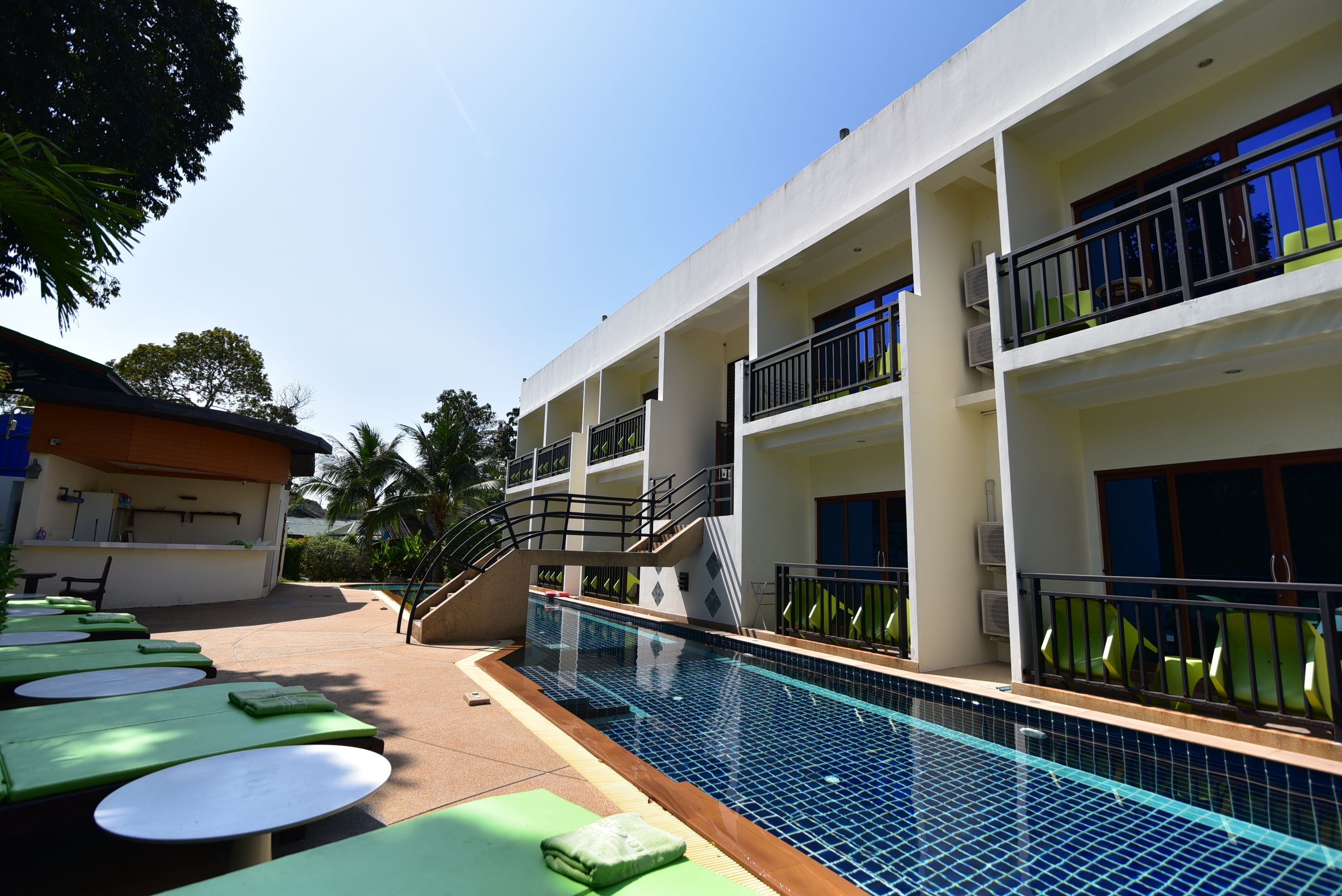 A hotel with a swimming pool, outdoor seating, and multiple balconies.
