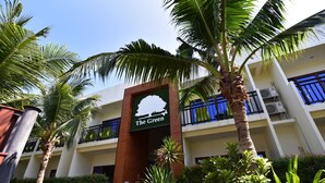Un hotel con un letrero que dice "The Green", con una decoración en tonos verde y blanco, palmeras y un edificio de varios pisos con balcones.