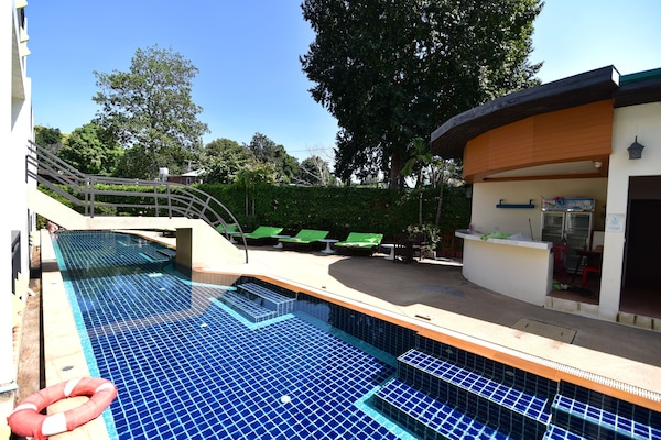 Una piscina al aire libre, sillones reclinables de piscina