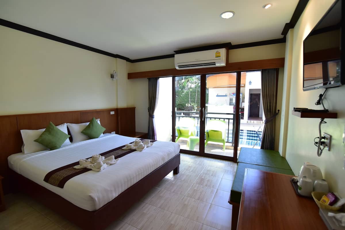 A hotel room with a large bed, a desk, and a view of the outside.