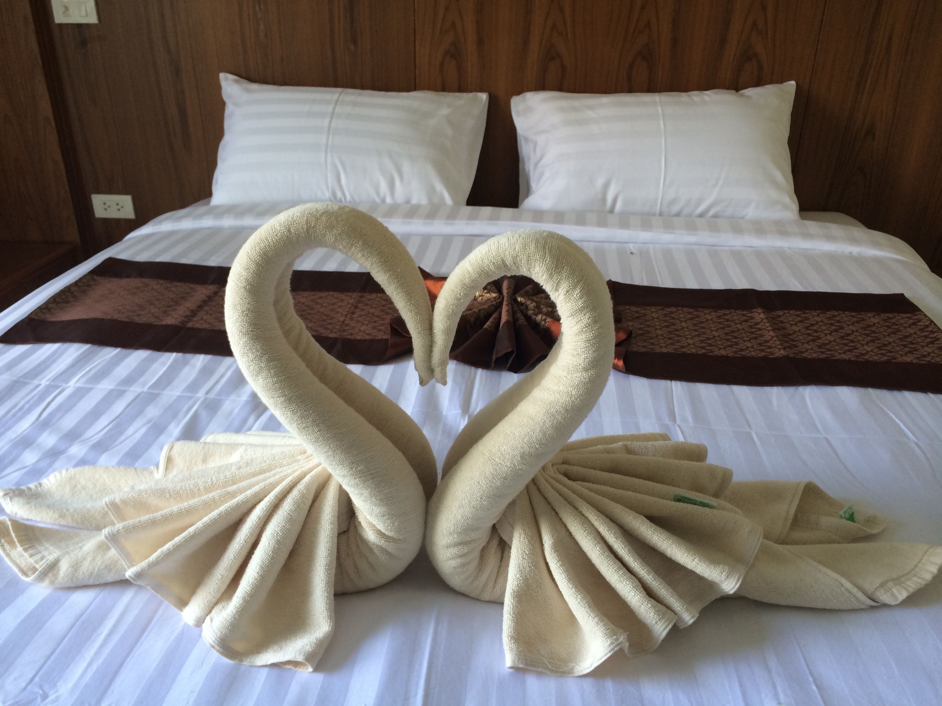 A bed with a heart-shaped towel arrangement.