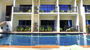 Un hotel de varios pisos con balcones, piscina y unidades de aire acondicionado.