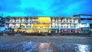 Et hotel med flere etager, altaner og udendørs siddepladser, beliggende tæt på stranden.