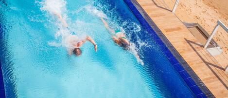 Una piscina con dos personas nadando.