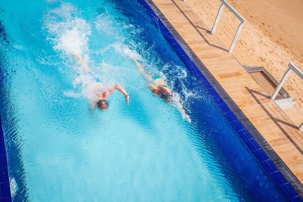 Una piscina al aire libre, sombrillas, tumbonas
