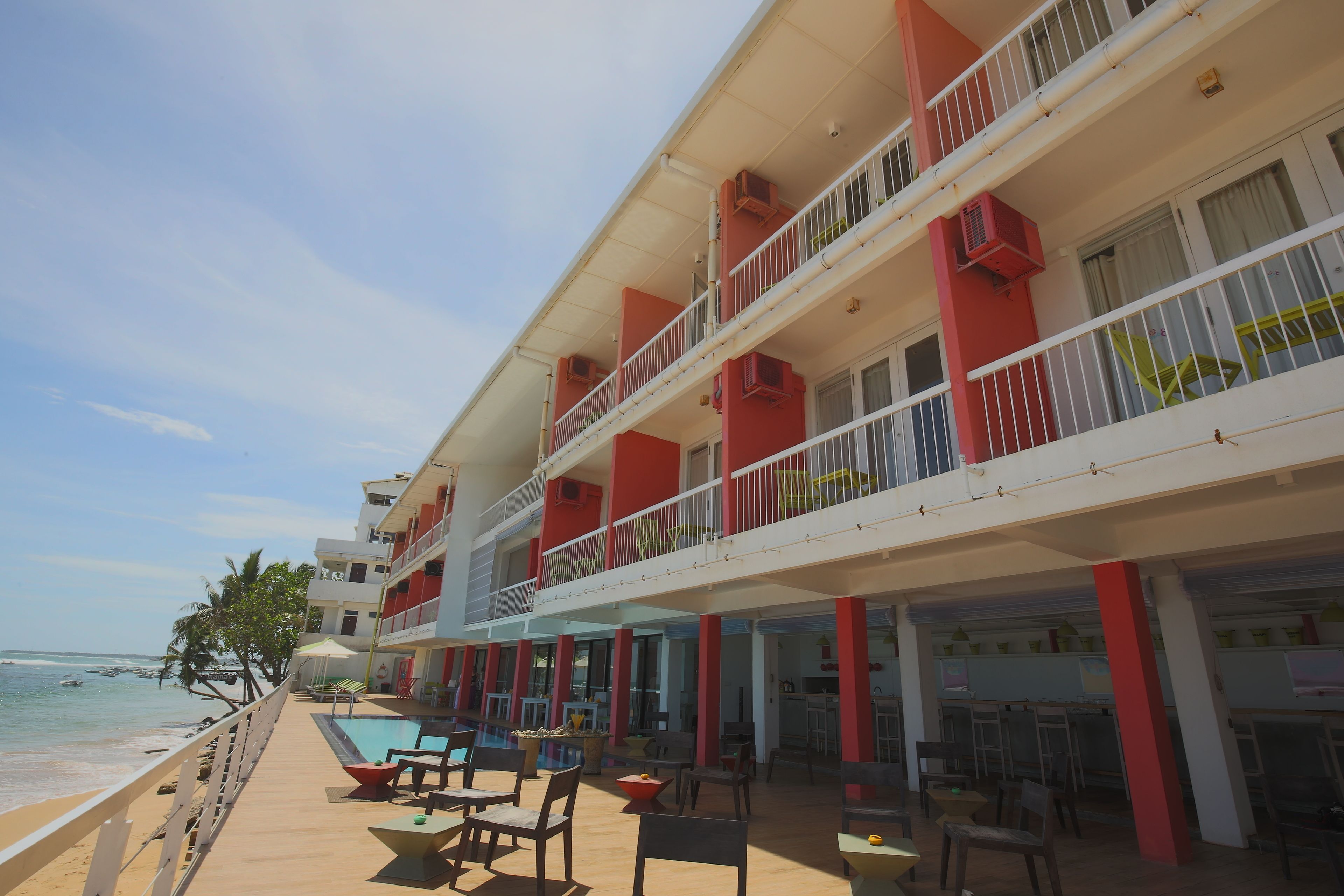 A multi-story hotel with balconies, outdoor seating, and a pool area.