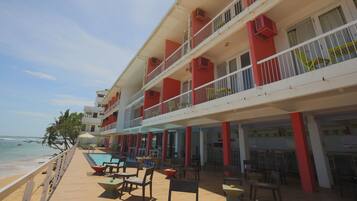 A multi-story hotel with balconies, outdoor seating, and a pool area.