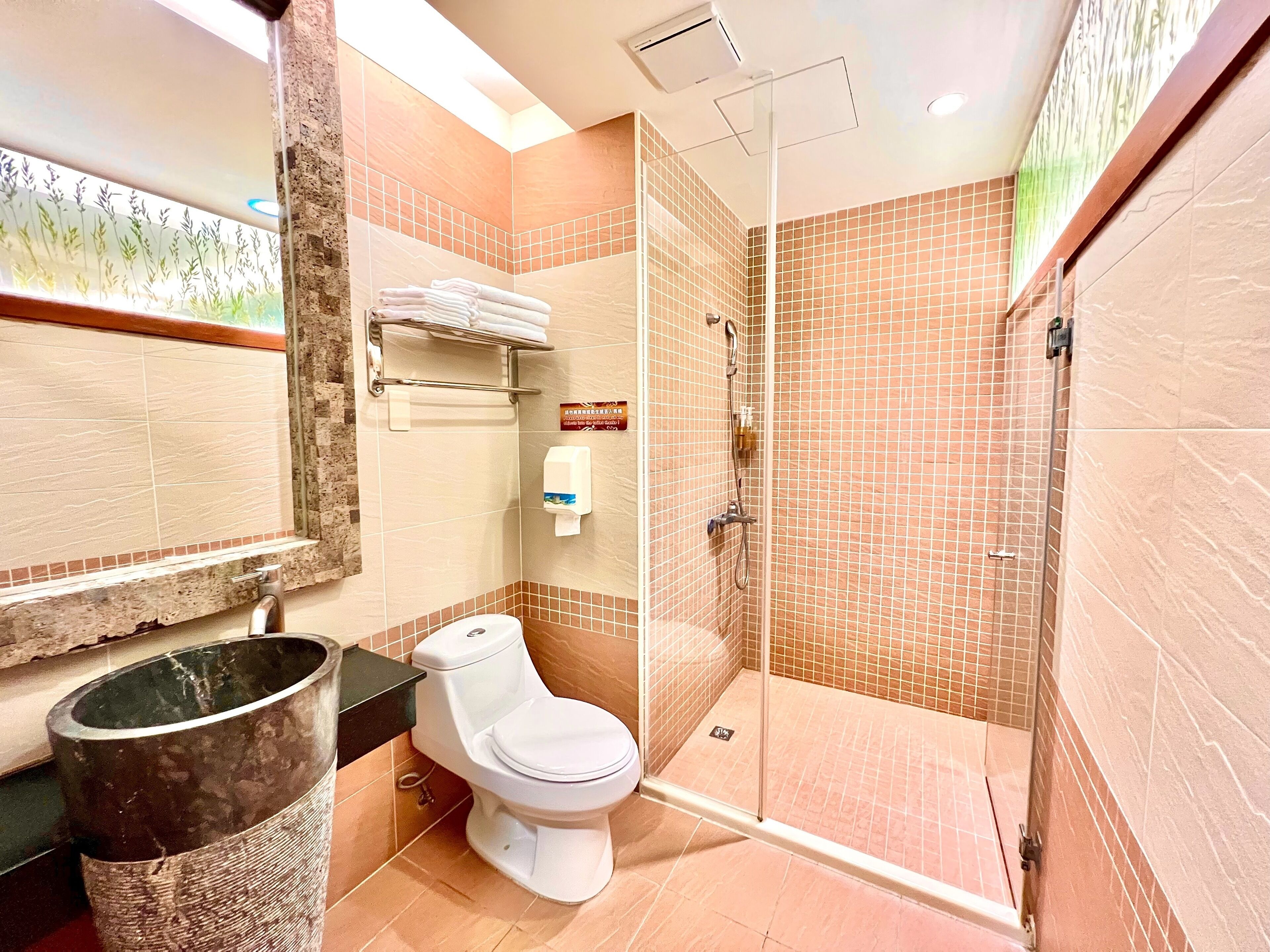 A bathroom with a toilet, a glass-enclosed shower, and a sink.
