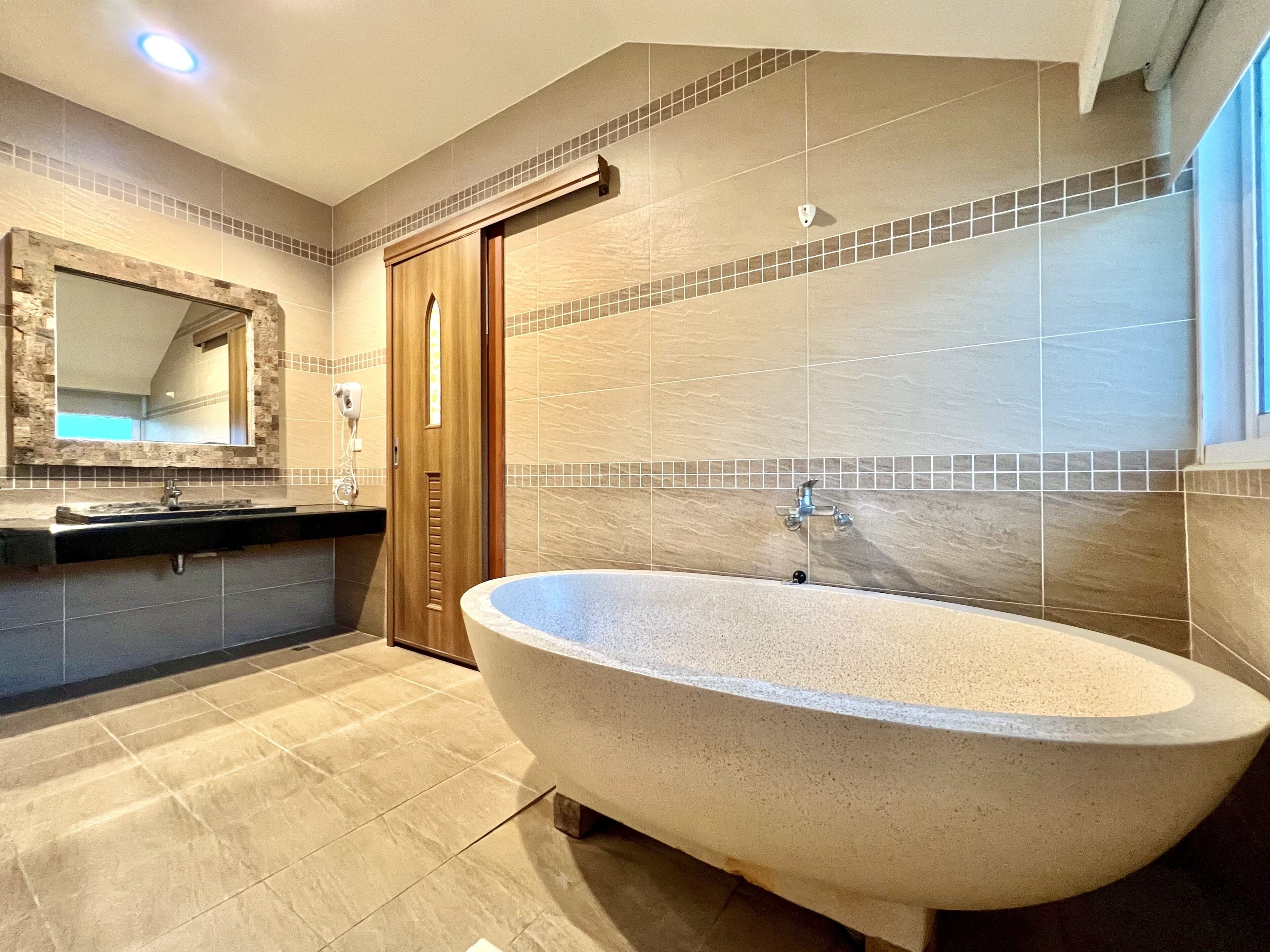 A modern bathroom with a freestanding bathtub, a vanity with a mirror, and a shower area.