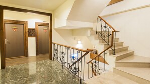 A modern hotel lobby with a marble staircase, wooden doors, and a metal railing. - Seasons Bali Fashion Inn (Hengchun)