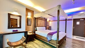 A four-poster bed with a canopy, a wooden desk with a chair, a bedside table, and a mirror on the wall. - Seasons Bali Fashion Inn (Hengchun)
