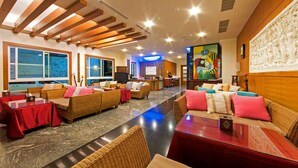 A spacious lobby with wicker sofas, red tables, and a reception desk. - Seasons Bali Fashion Inn (Hengchun)