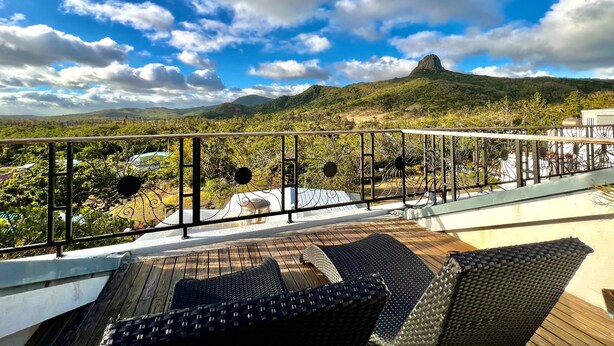A balcony with wicker furniture and a view of a mountainous landscape. - Seasons Bali Fashion Inn (Hengchun)