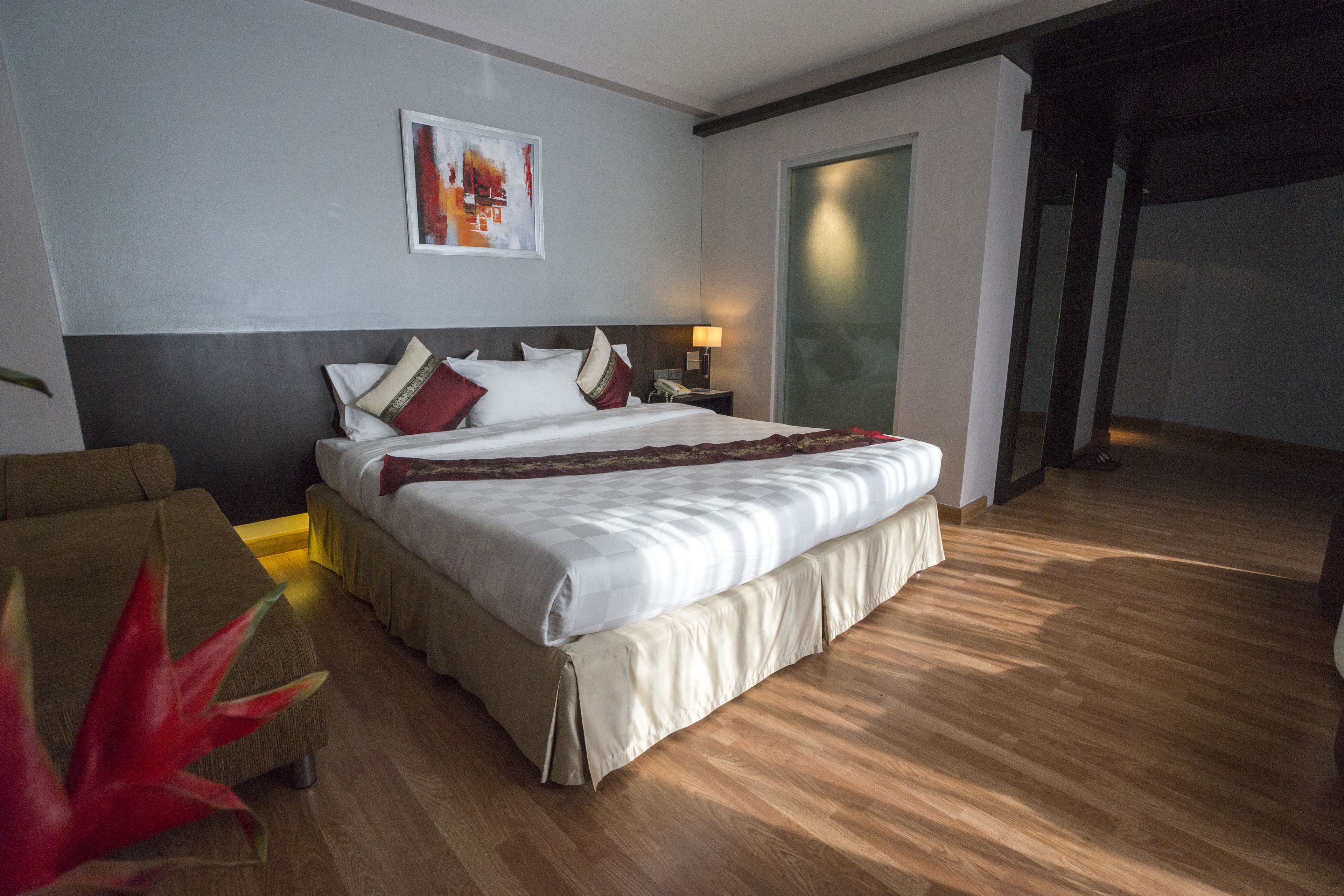 Ein Hotelzimmer mit einem großen Bett, einem Nachttisch, einer Lampe und einer Pflanze.