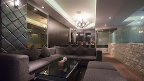 Una sala de estar moderna con un sofá modular, una mesa de centro de vidrio y una pared de acento de piedra.