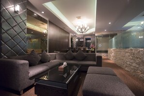 Een moderne woonkamer met een modulaire bank, een glazen salontafel en een wand van natuursteen.