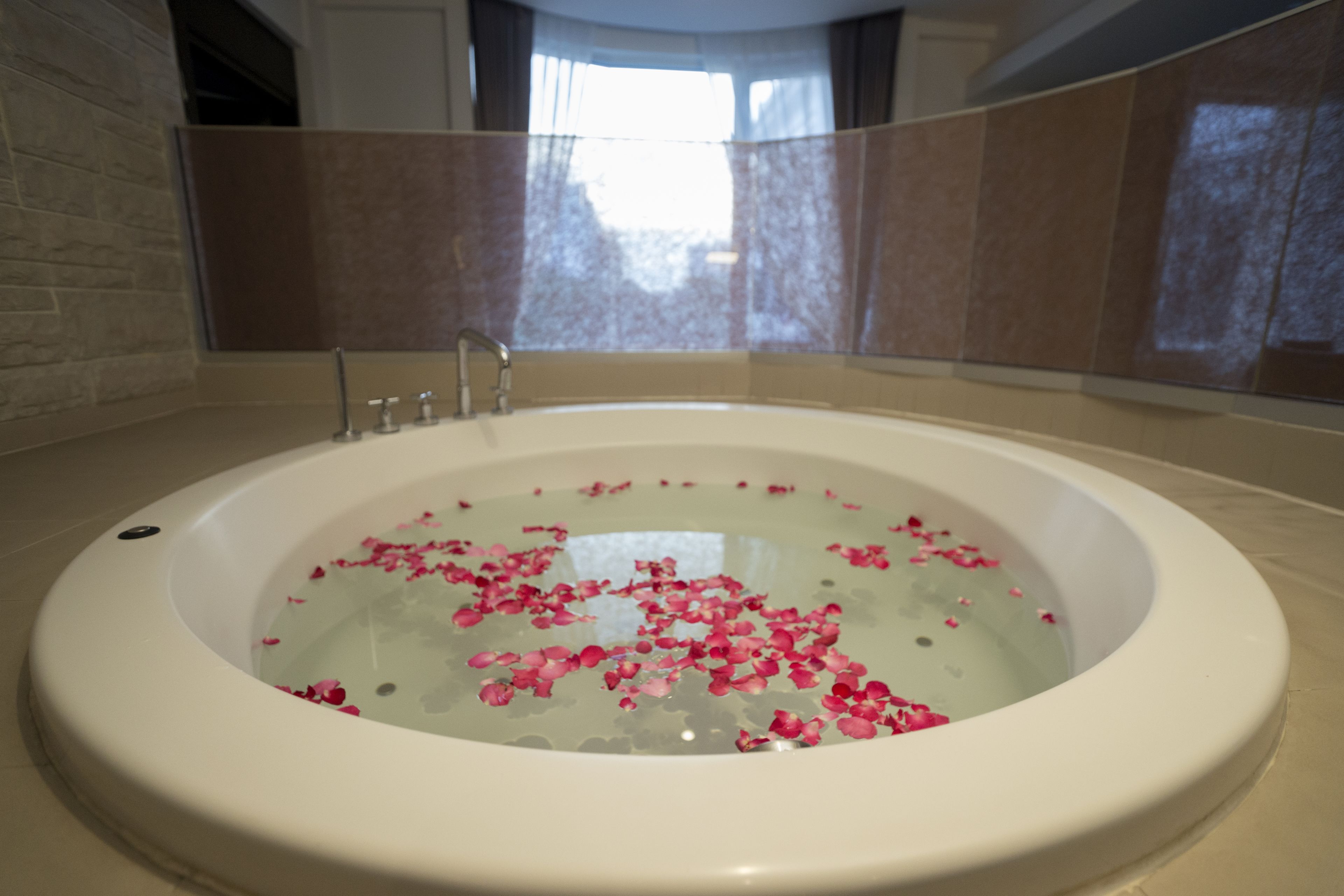 A bathtub filled with water and rose petals.