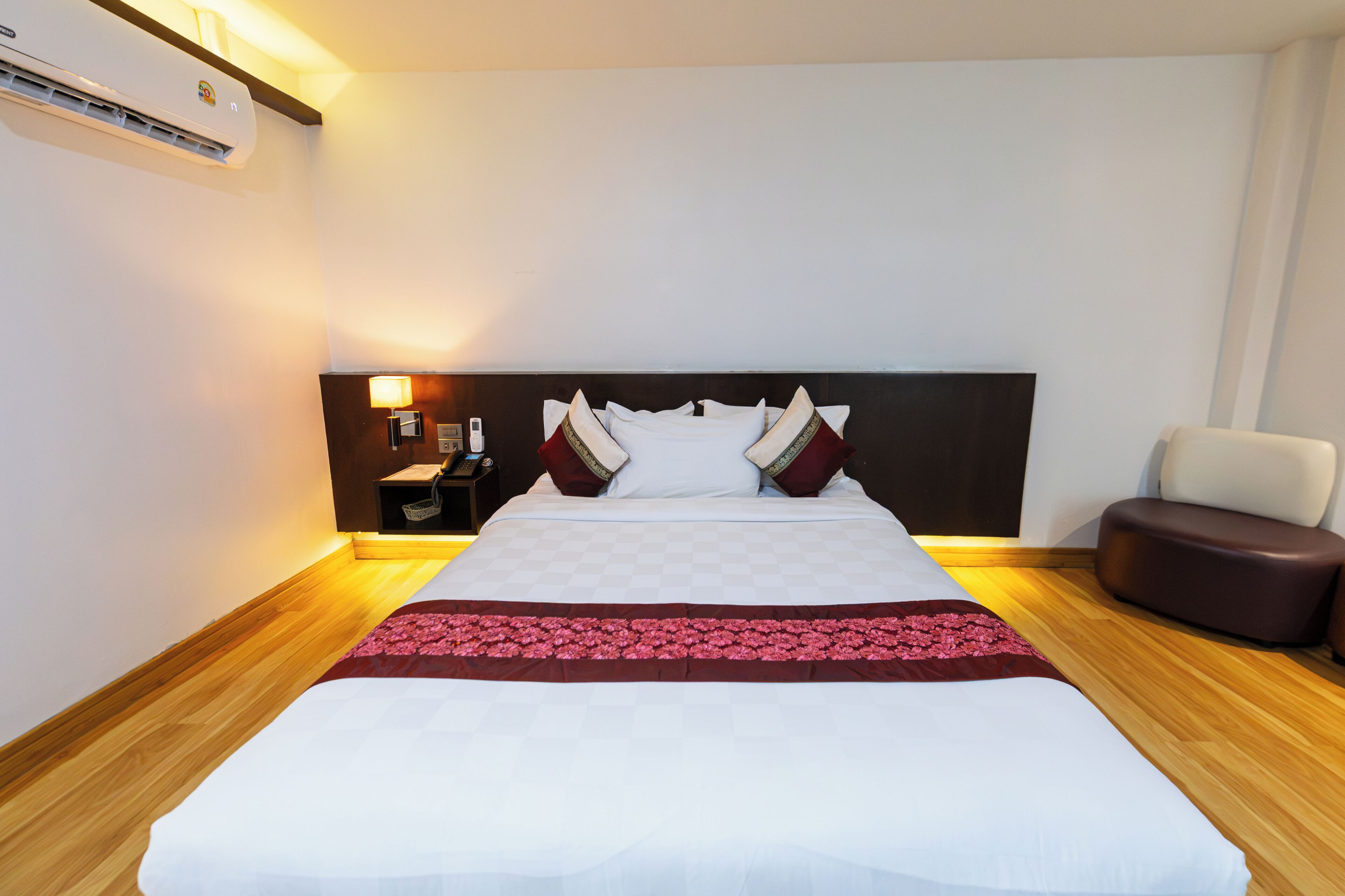 A hotel room with a large bed, bedside table, lamp, and a chair.