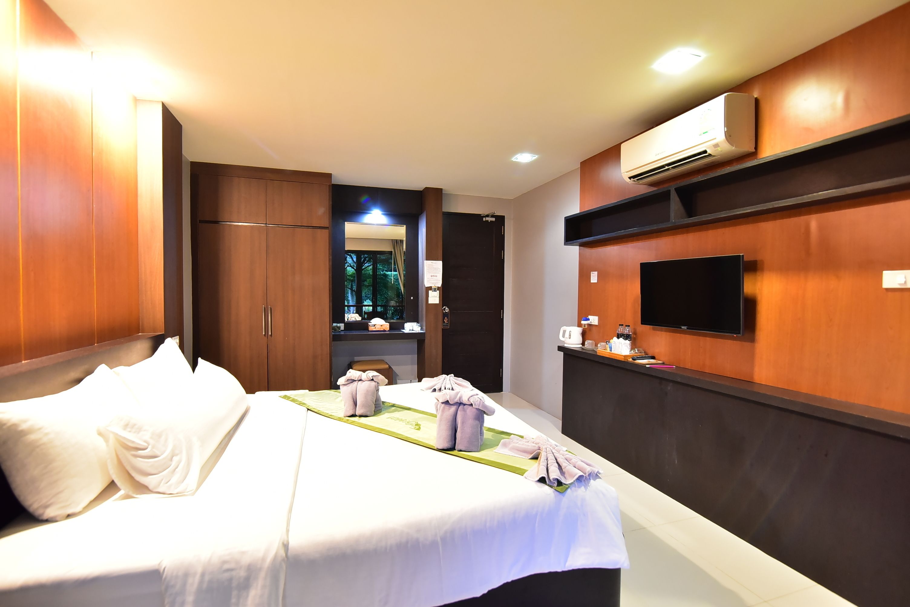 A hotel room with a bed, a flat-screen TV mounted on the wall, and a minibar.