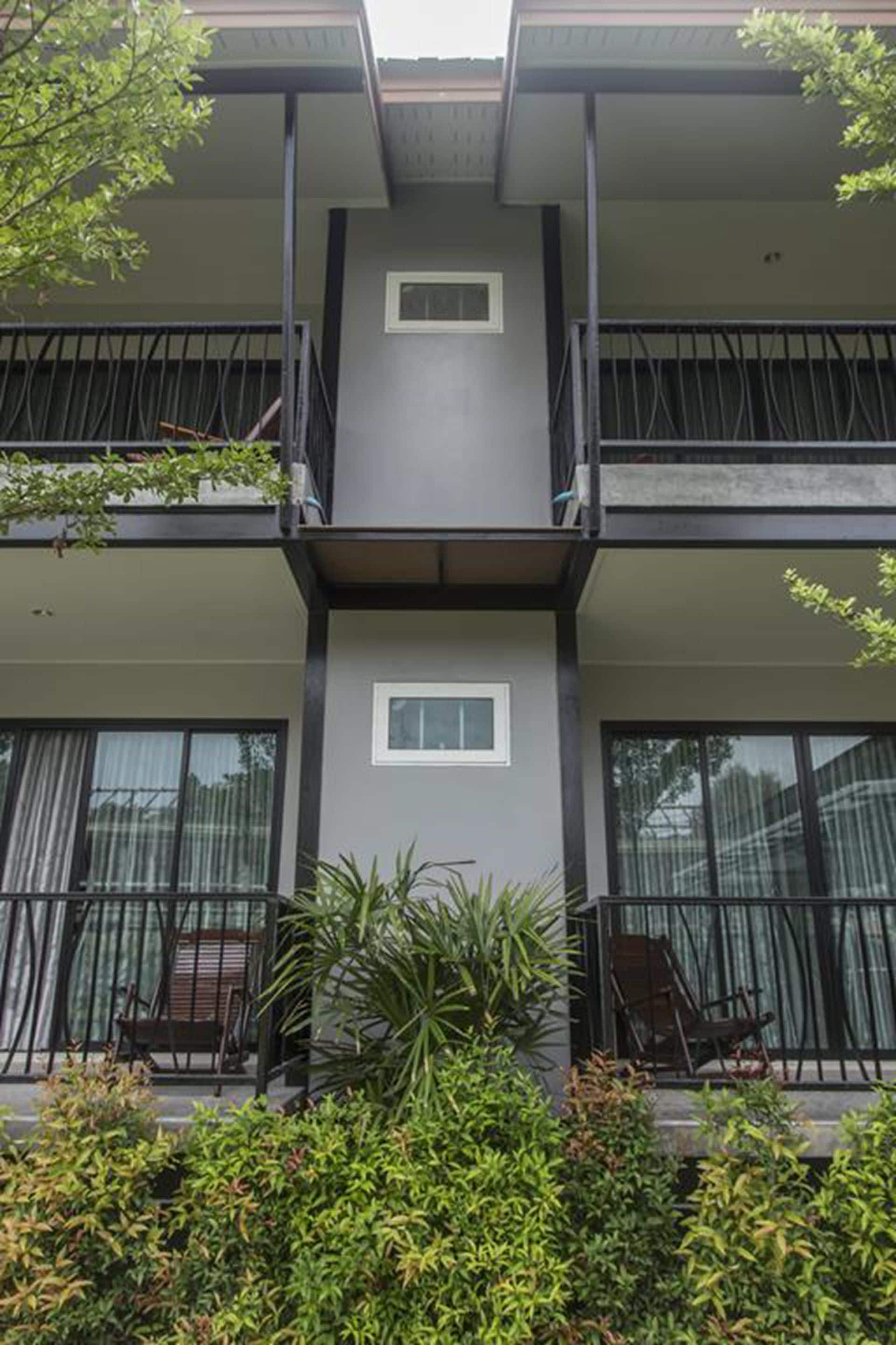 Un immeuble à plusieurs étages doté de balcons, de grandes fenêtres et de plantes en pot.