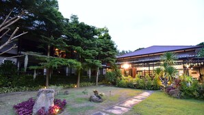 A well-maintained garden with stone pathways, lush greenery, and a traditional building with a tiled roof. - The Breeze Lipe Resort (Koh Lipe)