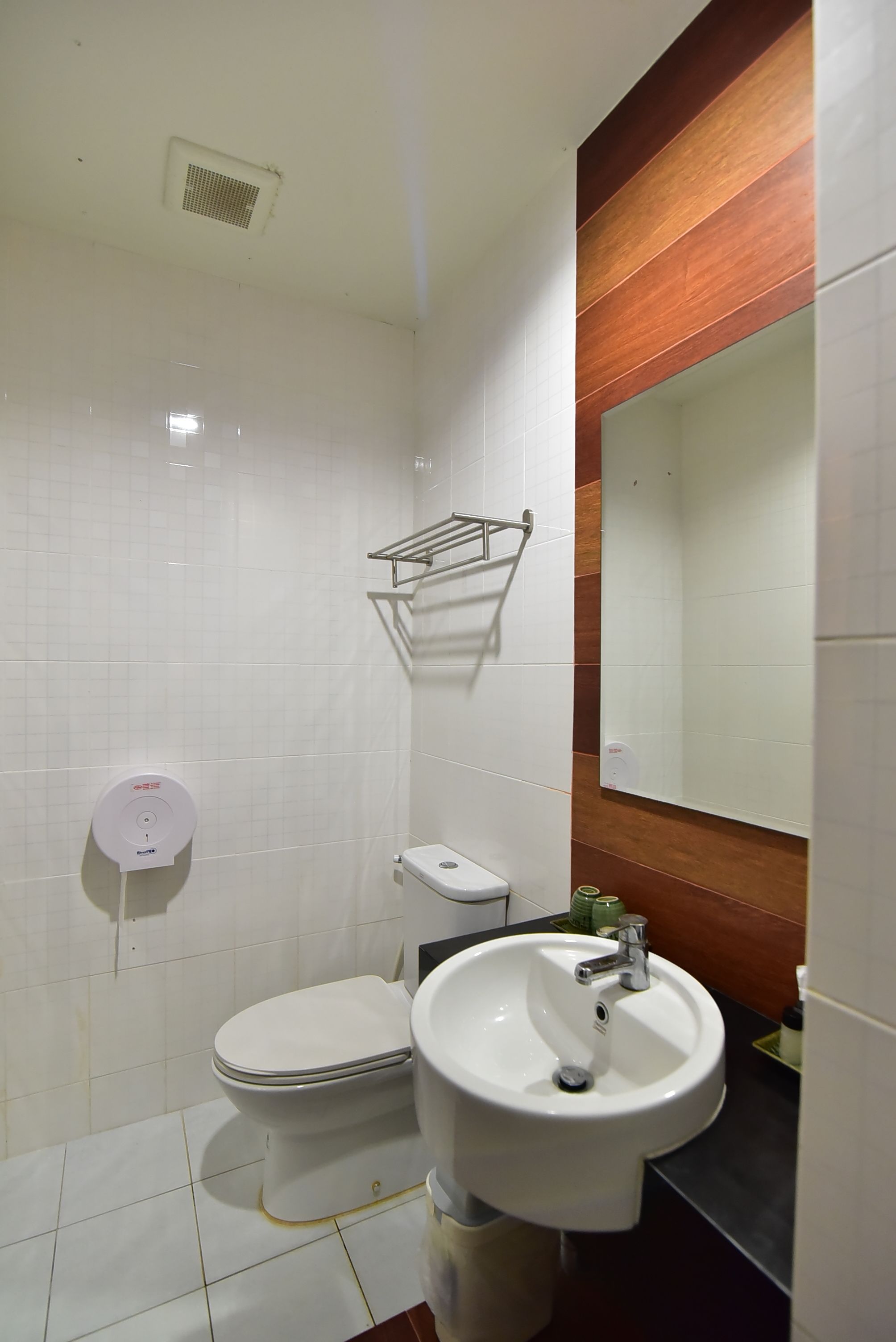 A bathroom with a toilet, sink, and mirror.