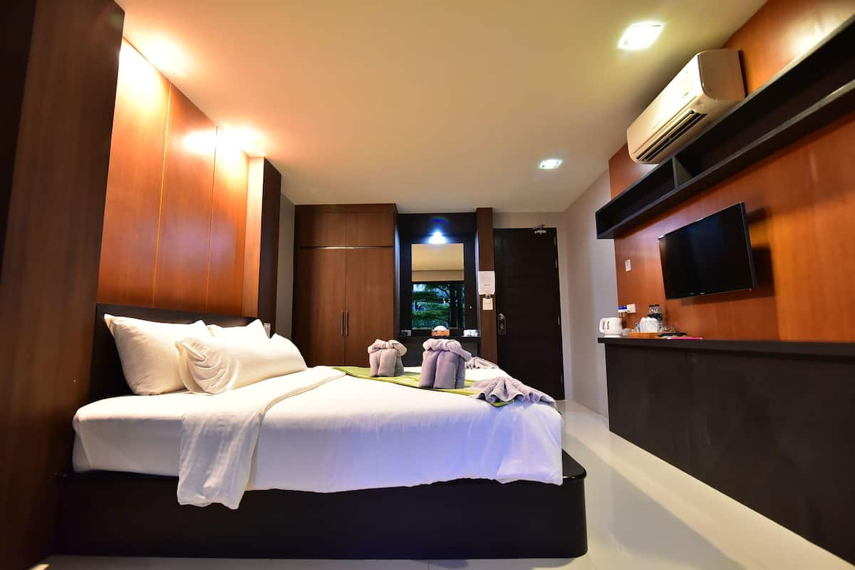 A modern hotel room with a large bed, a flat-screen TV, an air conditioning unit, and a wooden wall.