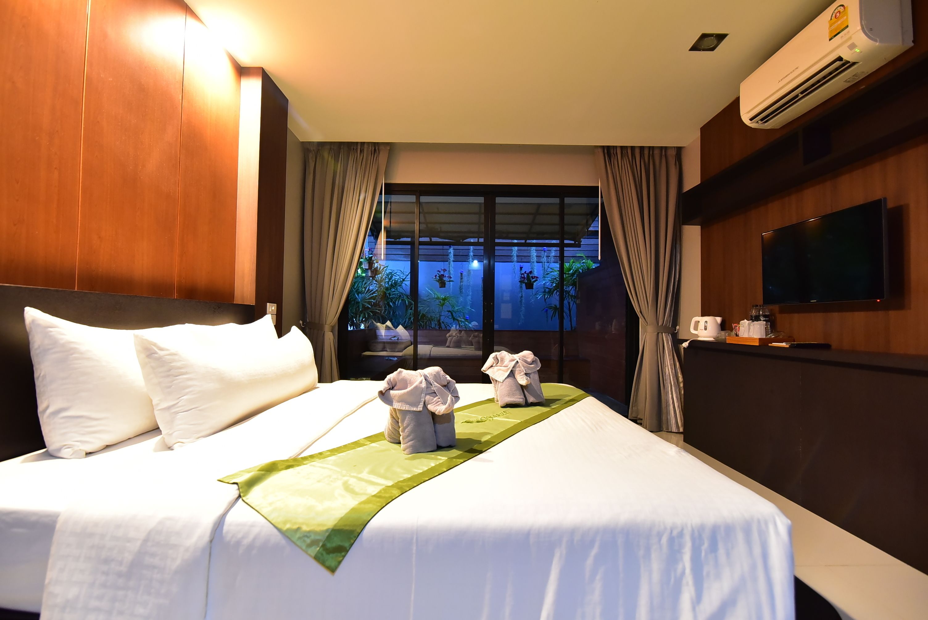A hotel room with a large bed, a flat-screen TV, and a view of the outdoors.