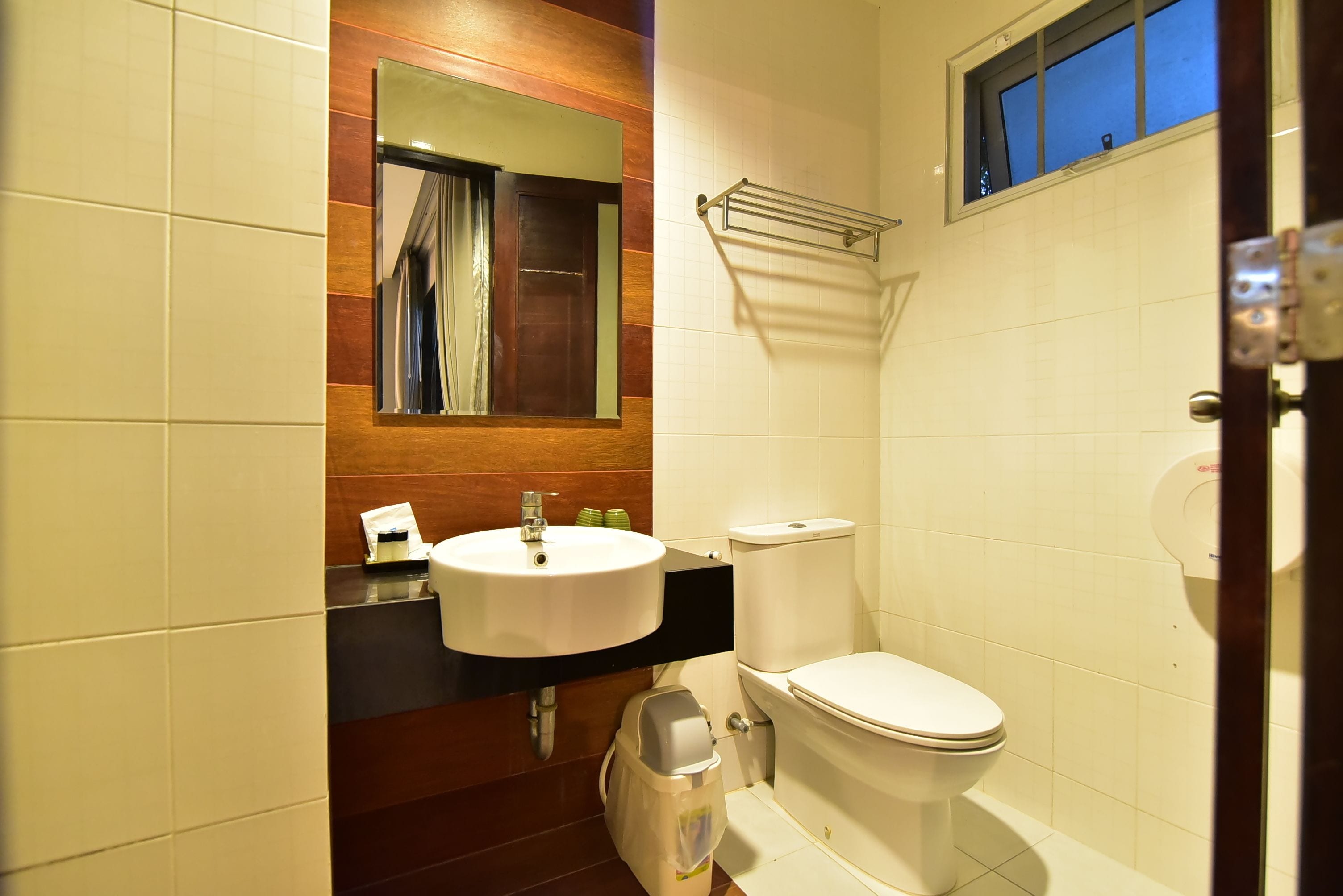 A bathroom with a white sink, mirror, and toilet.