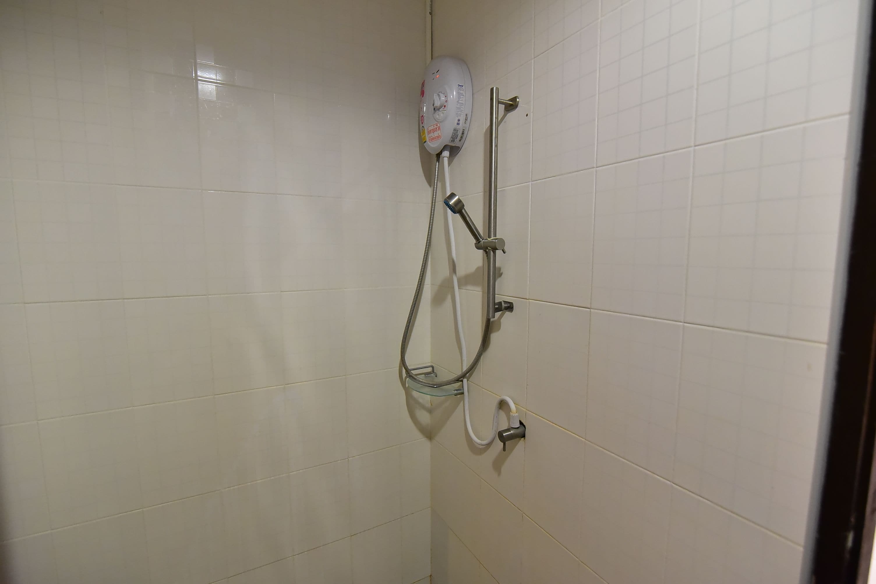 A shower with a handheld showerhead and a wall-mounted control valve.