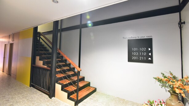 A modern hotel corridor with a wooden staircase, directional signs, and a vase of flowers. - The Breeze Lipe Resort (Koh Lipe)