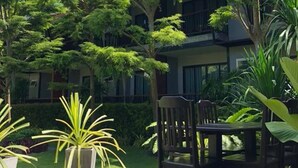 A covered outdoor area with a wooden deck, a table and chairs, and lush greenery including trees and potted plants. - The Breeze Lipe Resort (Koh Lipe)