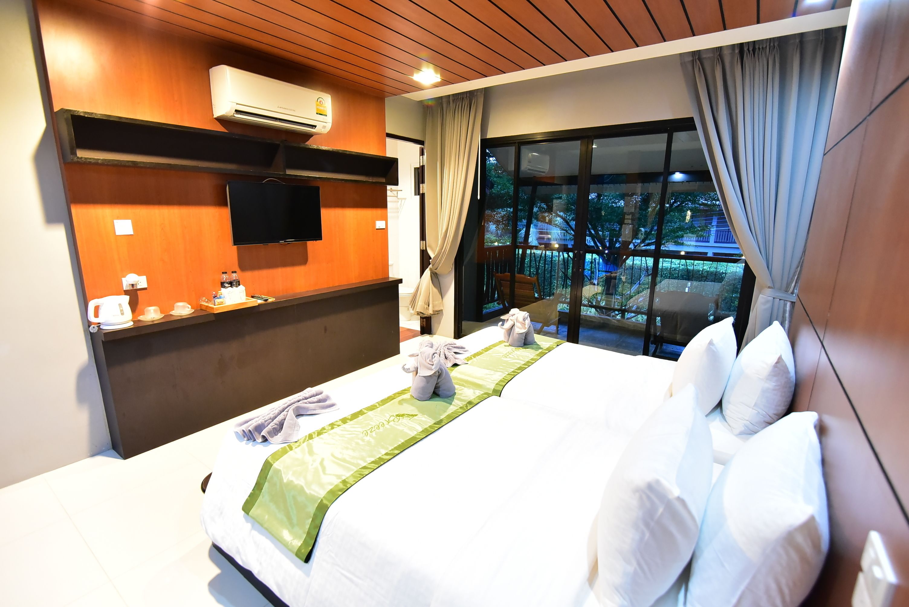 Habitación de hotel con una cama grande, televisión de pantalla plana, minibar y balcón con vistas al exterior.