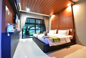 Un dormitorio moderno con una cama grande, un banco empotrado, una ventana con cortinas y vistas a zonas verdes.